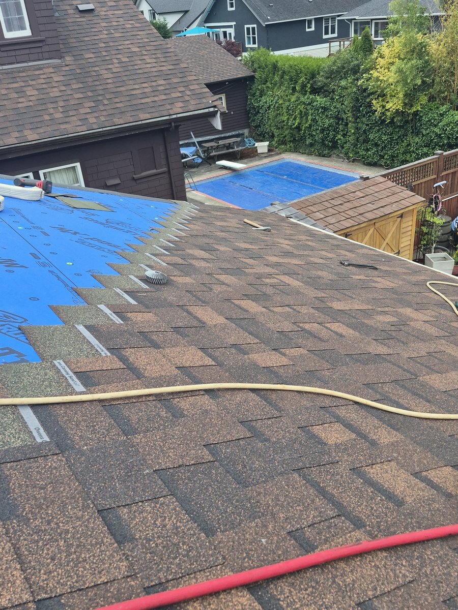 Shingles being installed beside blue roof underlayment