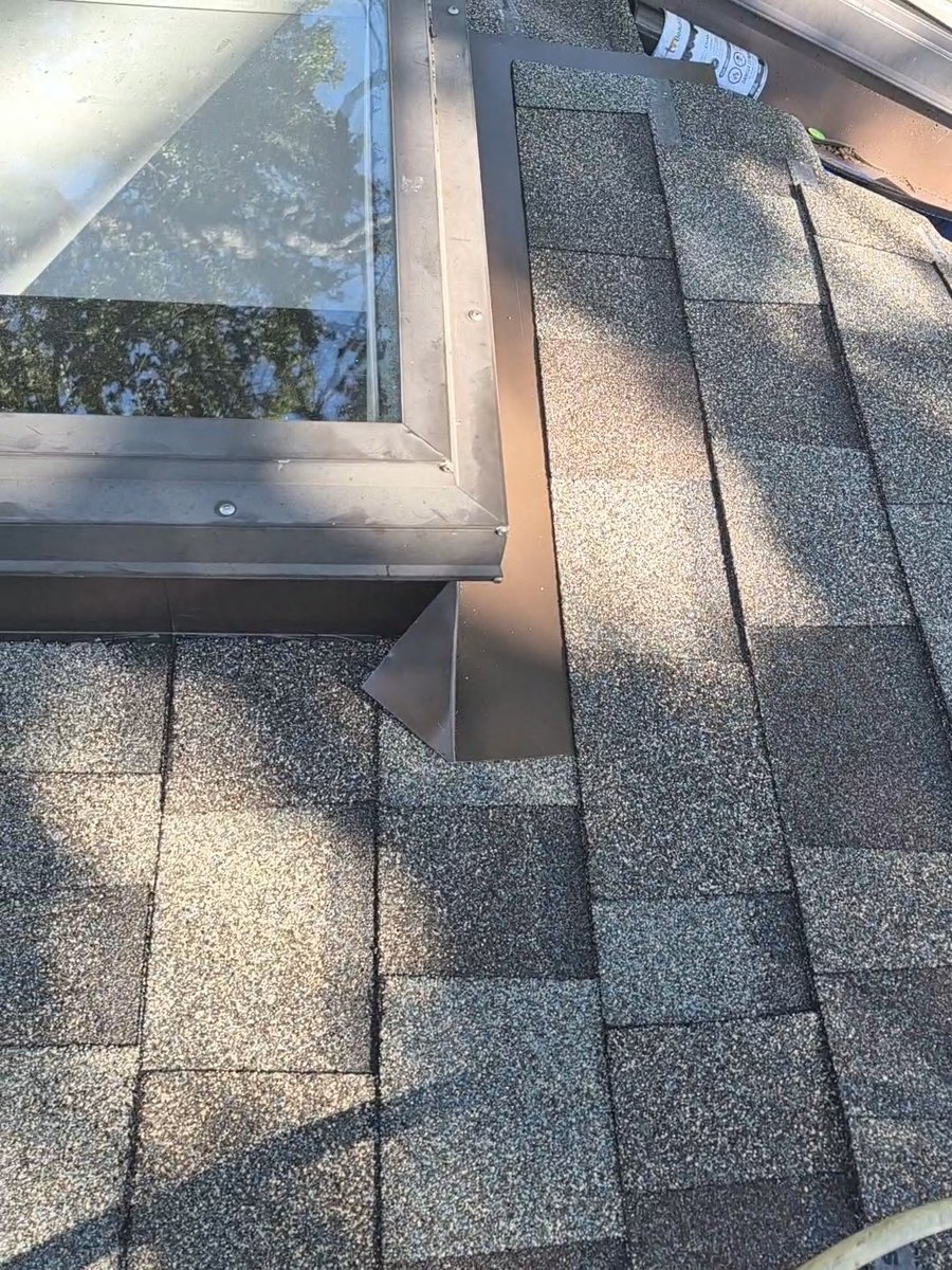 Metal flashing around a skylight on a gray shingle roof