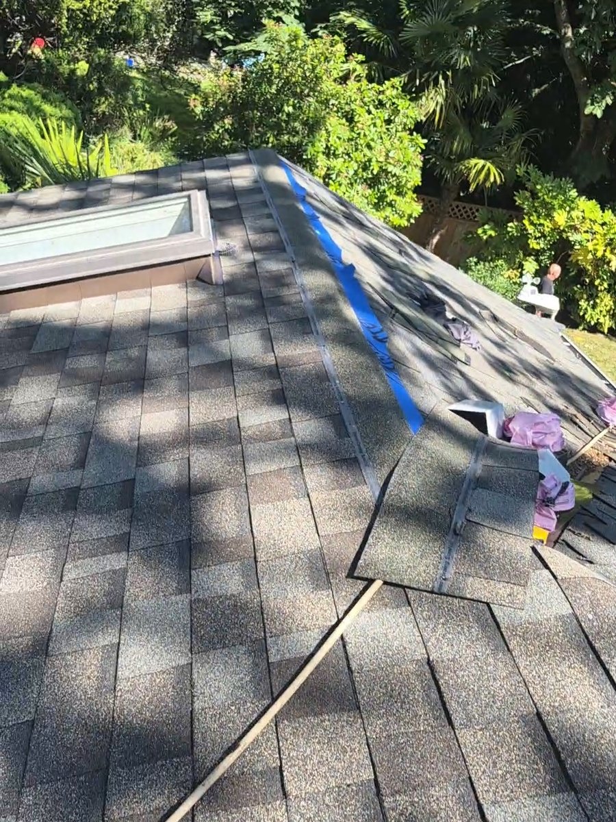 Shingled roof near a skylight with materials along the roof edge