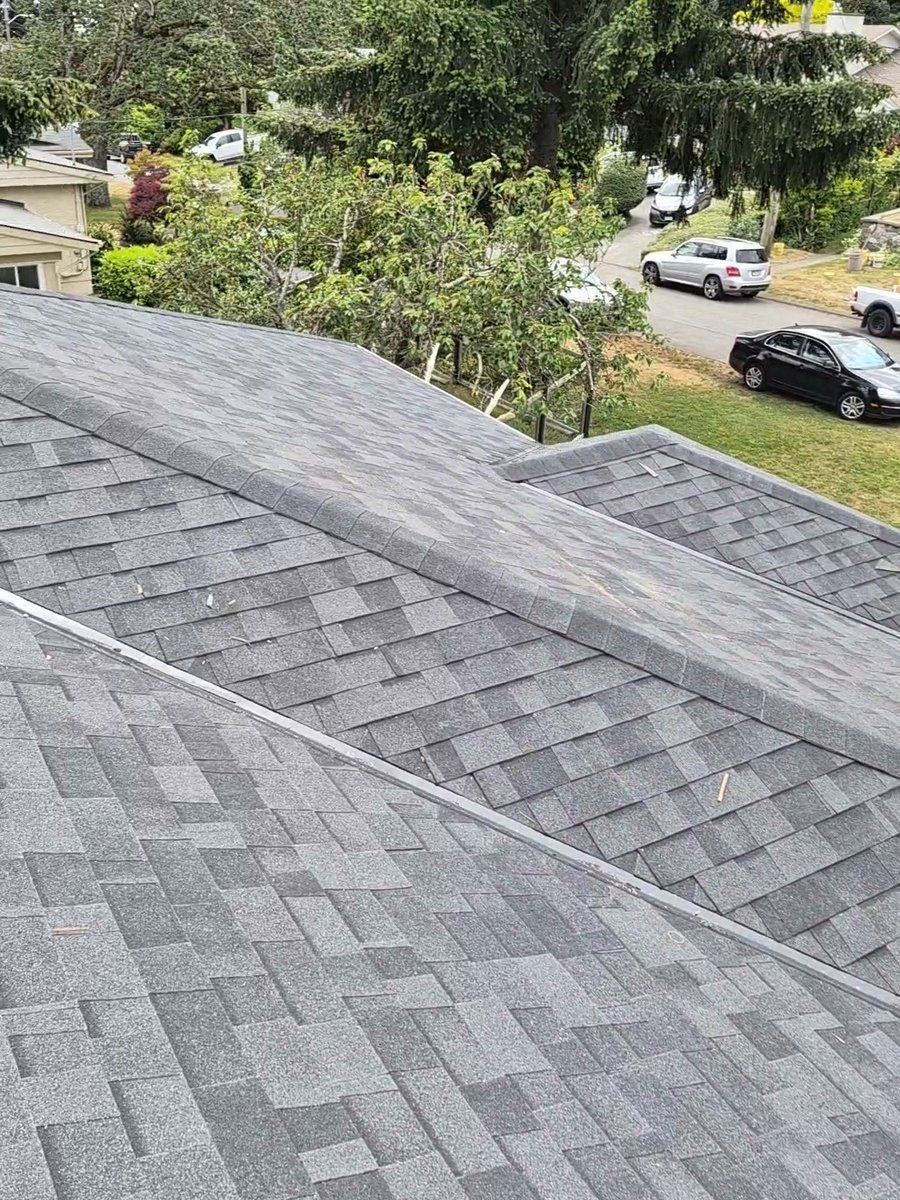 Finished gray shingle roof with intersecting slopes