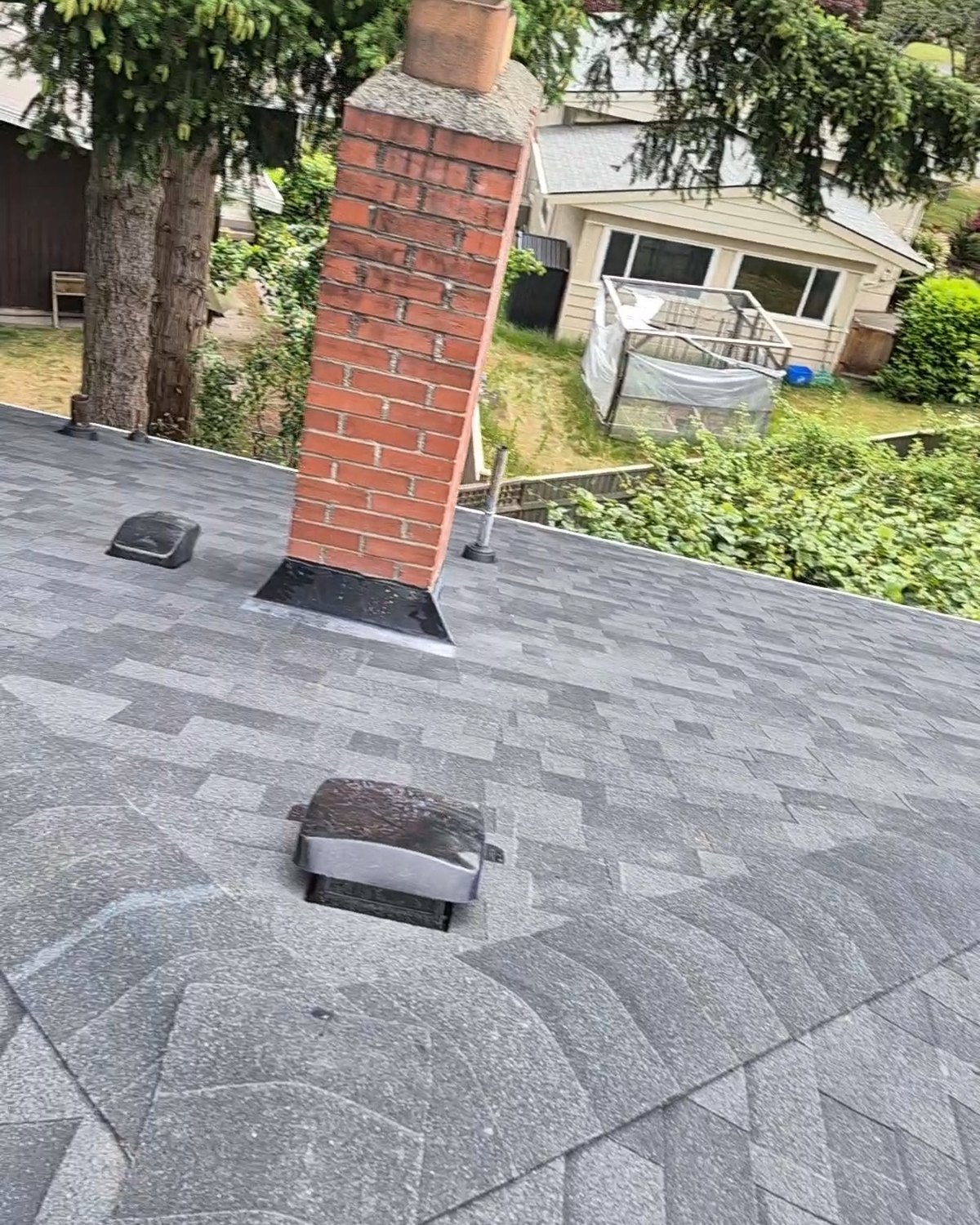 Gray shingle roof with a brick chimney and roof vent