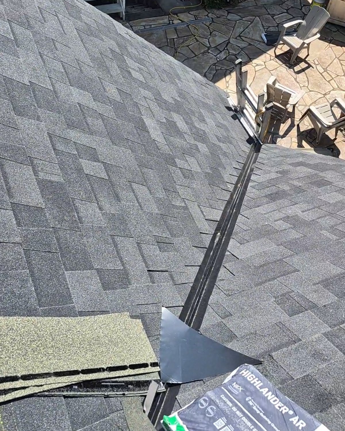 Gray shingles meeting at a metal-flashed roof valley