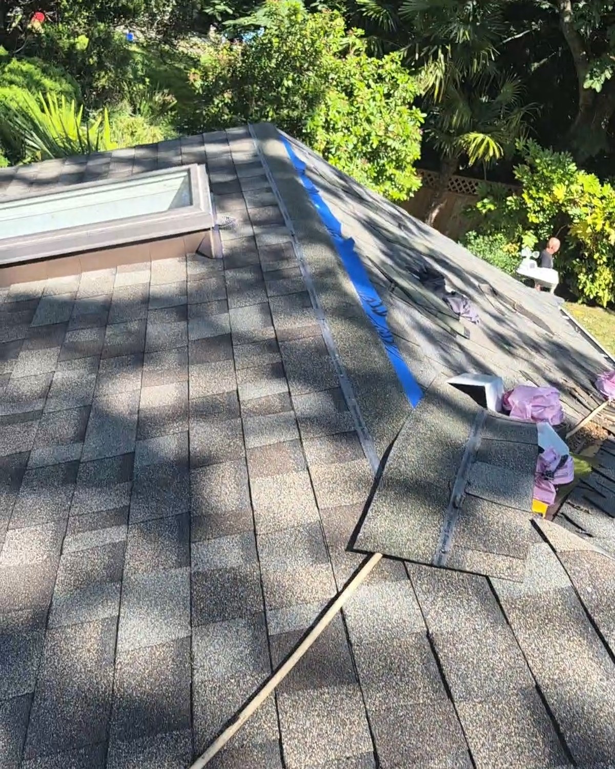 Shingled roof beside a skylight with materials along its edge