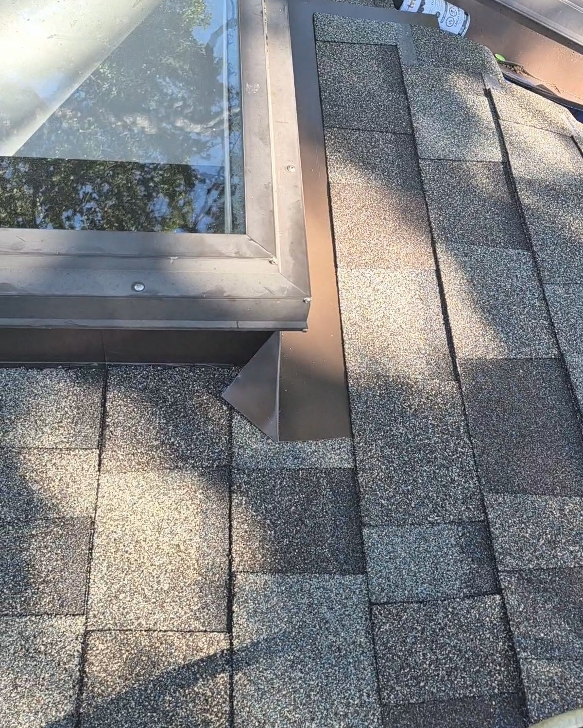 Skylight with metal flashing set into gray shingles